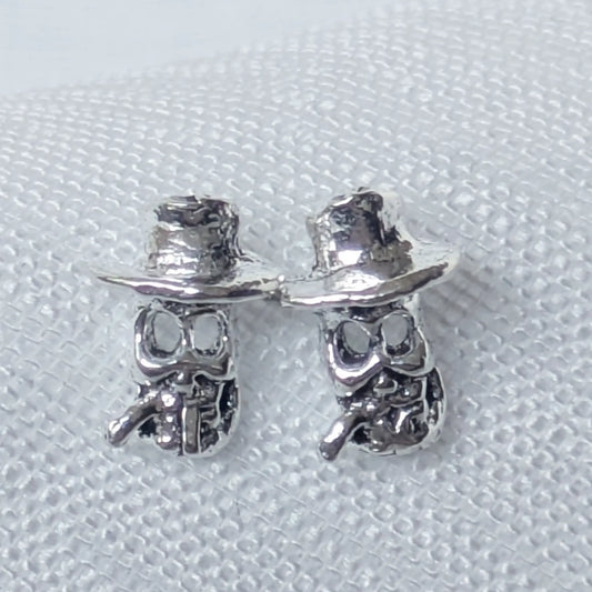 Detailreiche Nahaufnahme der 925 Silber Totenkopf Ohrringe mit Hut und Zigarre.