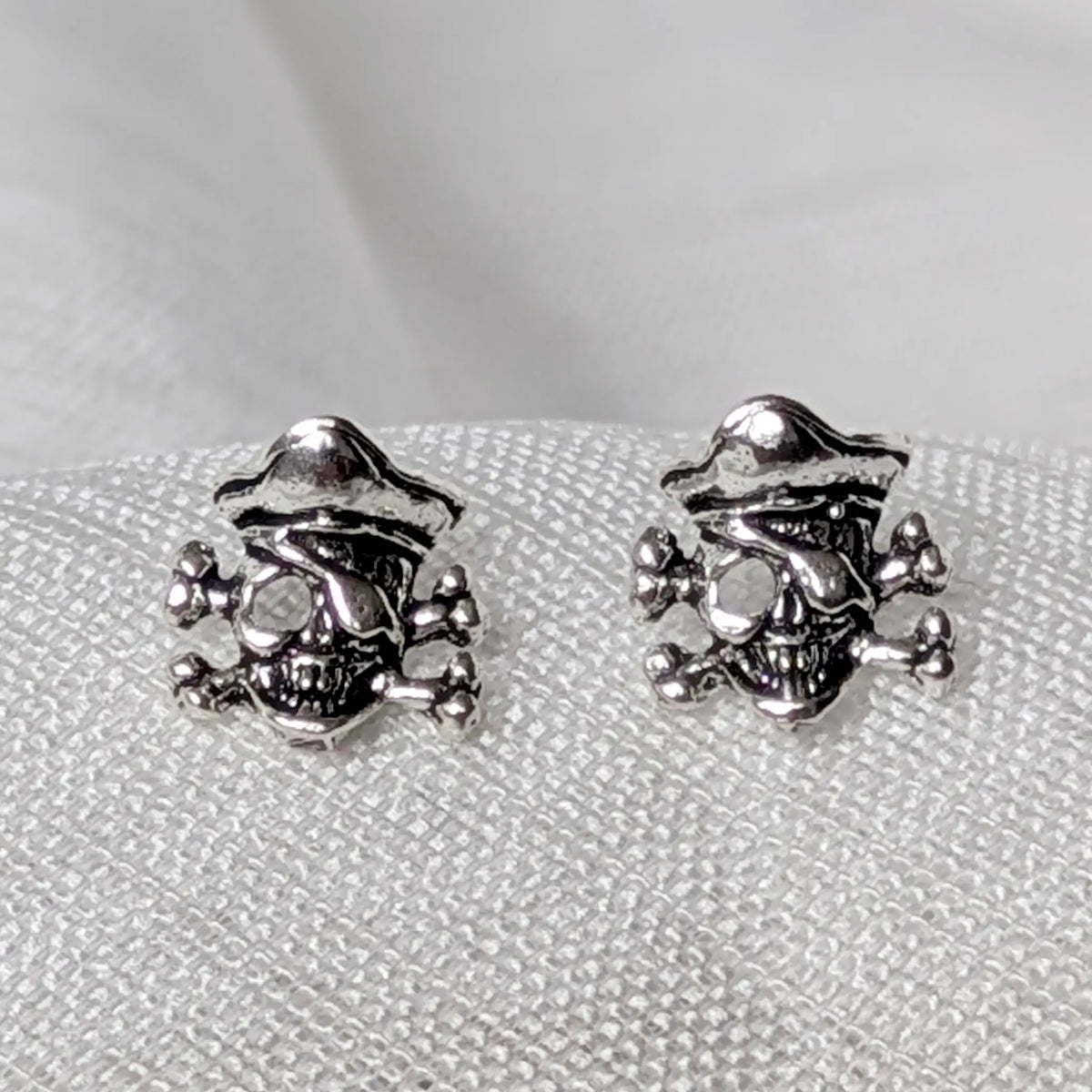 Detaillierte Nahaufnahme von Totenkopf Piraten Ohrsteckern aus 925 Silber mit Augenklappe und Hut.