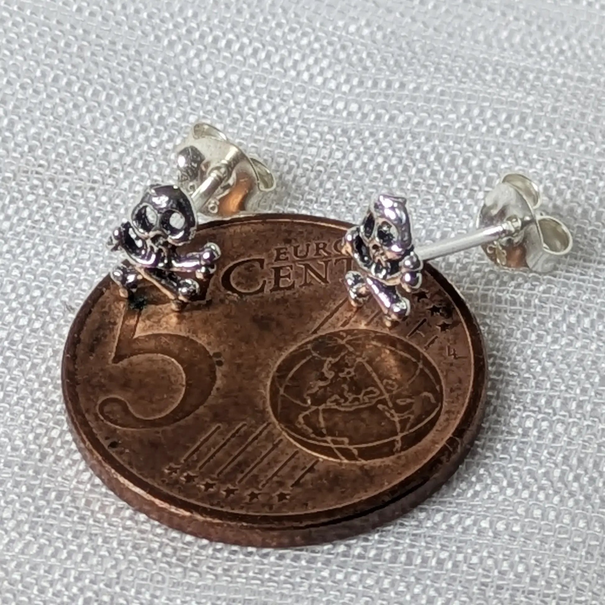 Größenvergleich: Kleine Totenkopf Silberohrstecker auf einer 5-Cent-Münze.