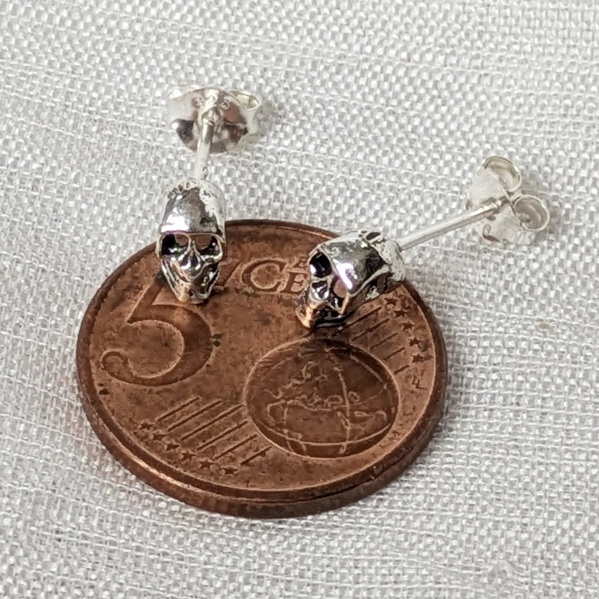 Größenvergleich kompakte Totenkopf Ohrstecker aus Silber auf 5-Cent-Münze