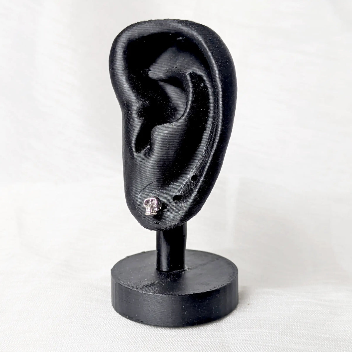 Kleine Totenkopf Ohrstecker 925 Silber präsentiert an einem schwarzen Ohr-Display