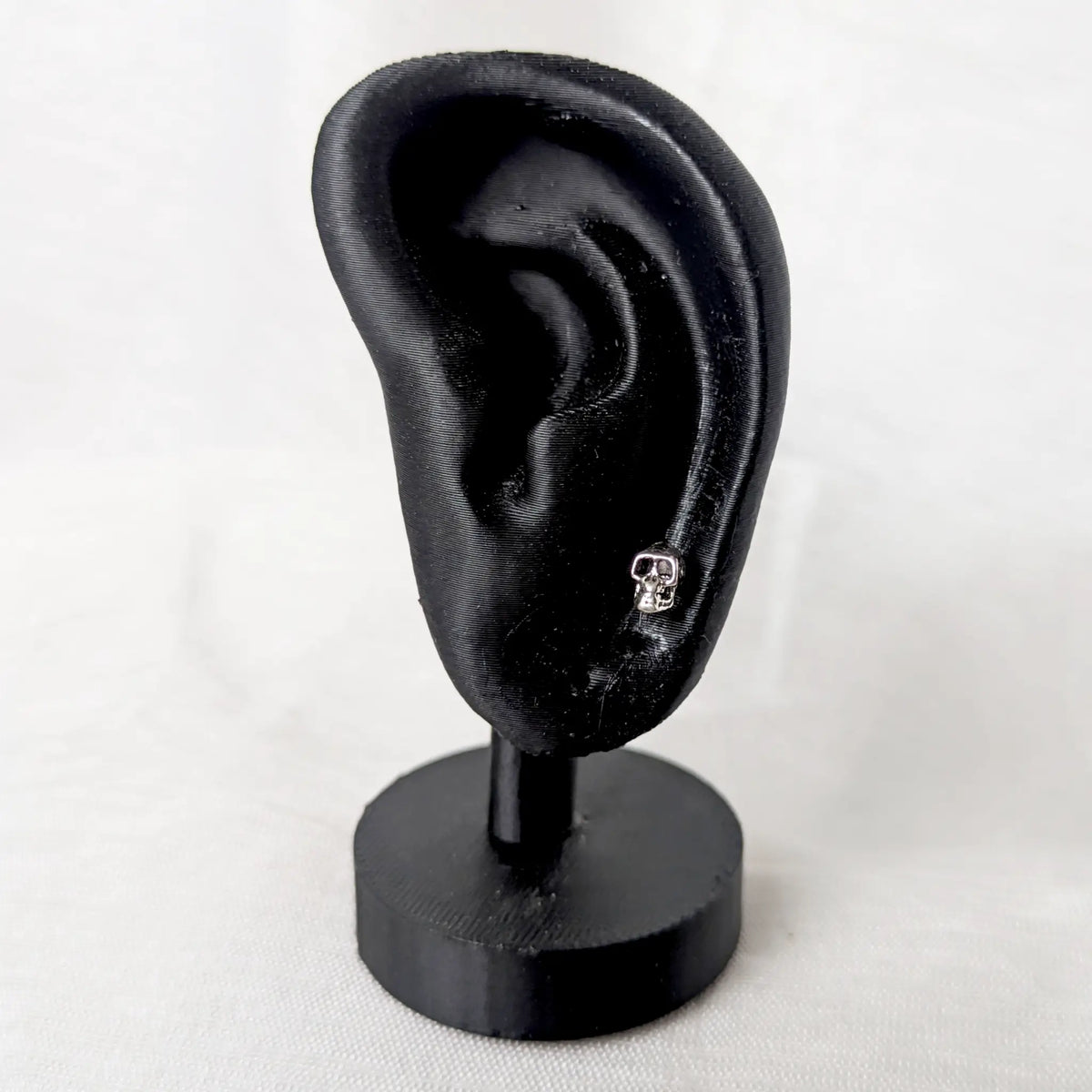 Totenkopf Ohrstecker 925 Silber präsentiert an einem schwarzen Ohr-Display