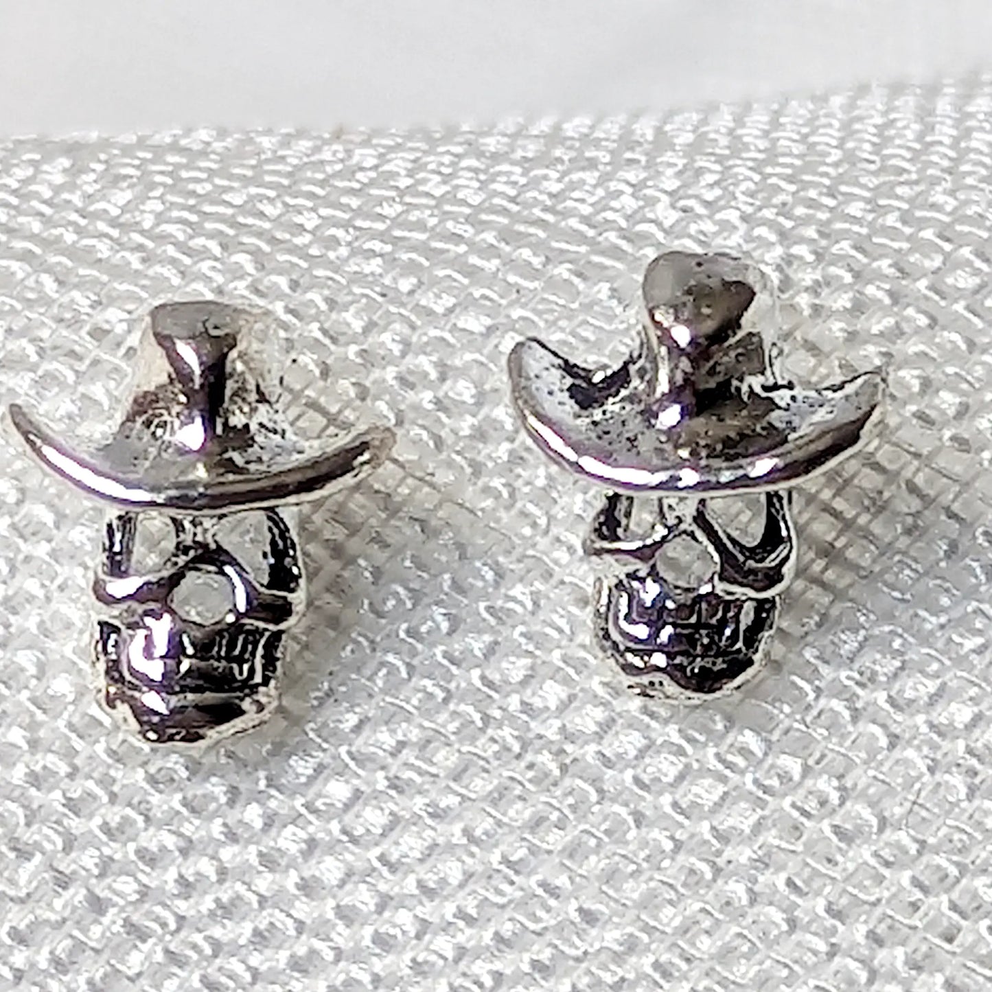 Detailierte Nahaufnahme von zwei Totenkopf Ohrsteckern aus 925 Sterling Silber mit plastischem Cowboyhut.