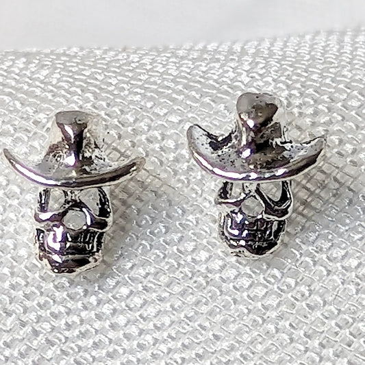 Detailierte Nahaufnahme von zwei Totenkopf Ohrsteckern aus 925 Sterling Silber mit plastischem Cowboyhut.