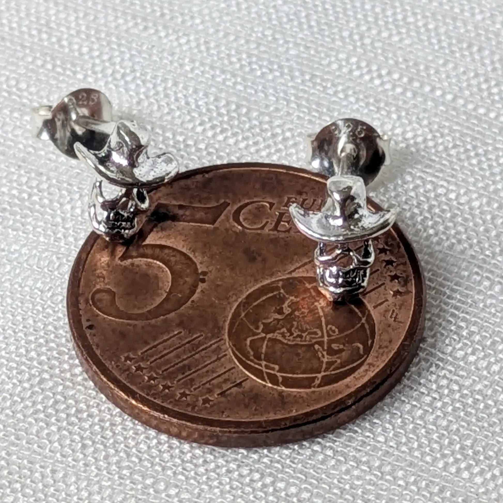 Größenvergleich der Miniatur-Skull-Ohrstecker aus Silber platziert auf einer 5-Cent-Münze