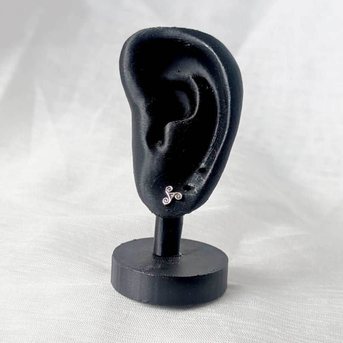 Zierlicher Triskele Silber-Ohrstecker, dezent präsentiert an einem schwarzen 3D-Ohr-Display