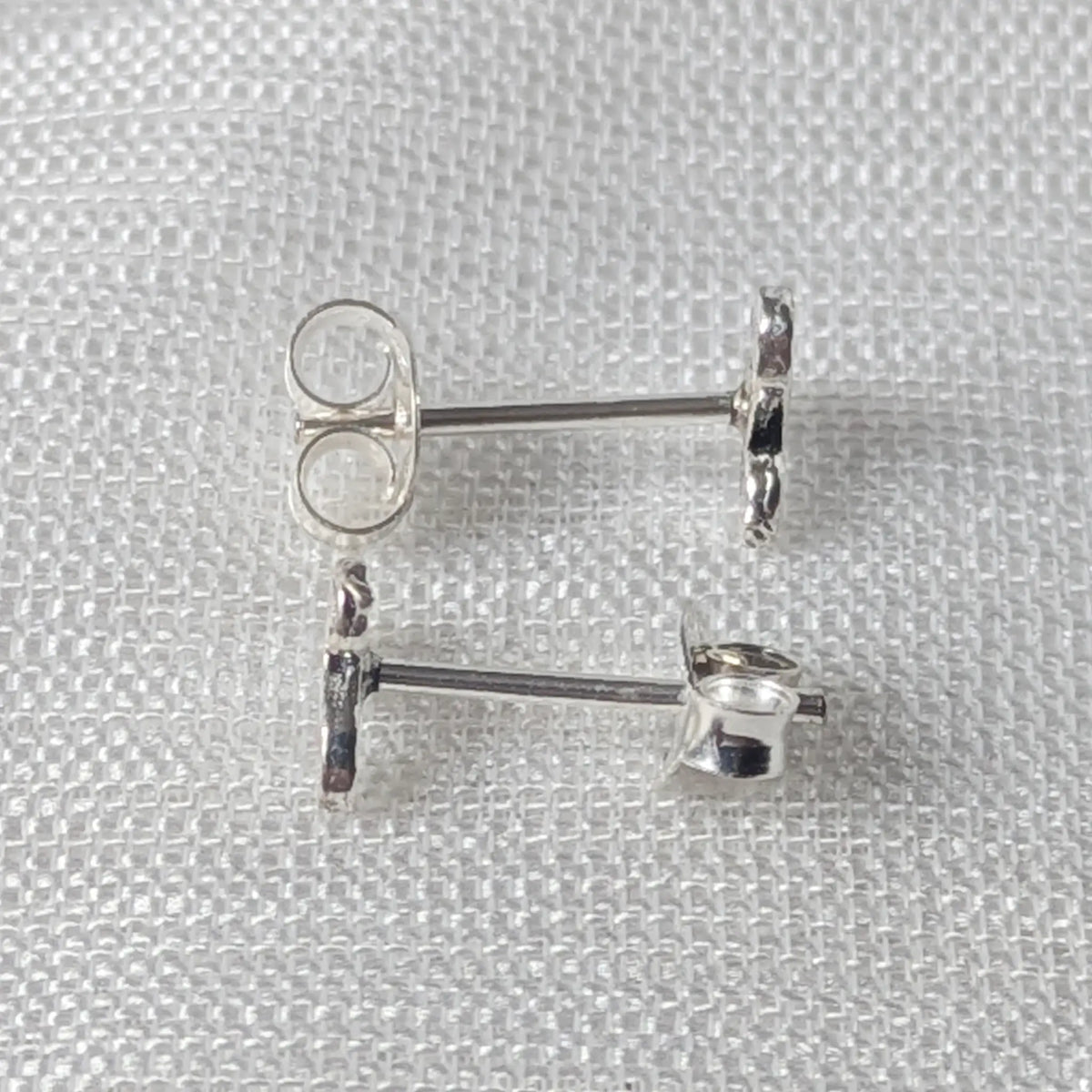 Seitliche Perspektive der Silberohrstecker mit Fokus auf den geraden Steckerstift und das flache Keltische Symbol.
