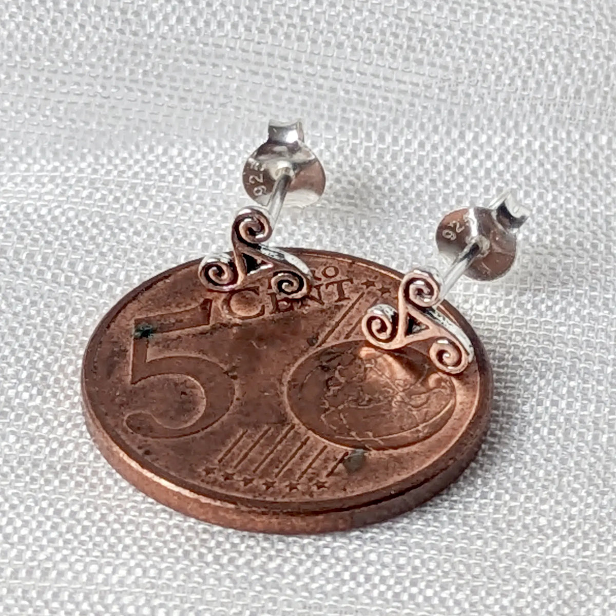 Größenvergleich: Die filigranen keltischen 925 Silber Ohrstecker flach liegend auf einer 5-Cent-Münze.