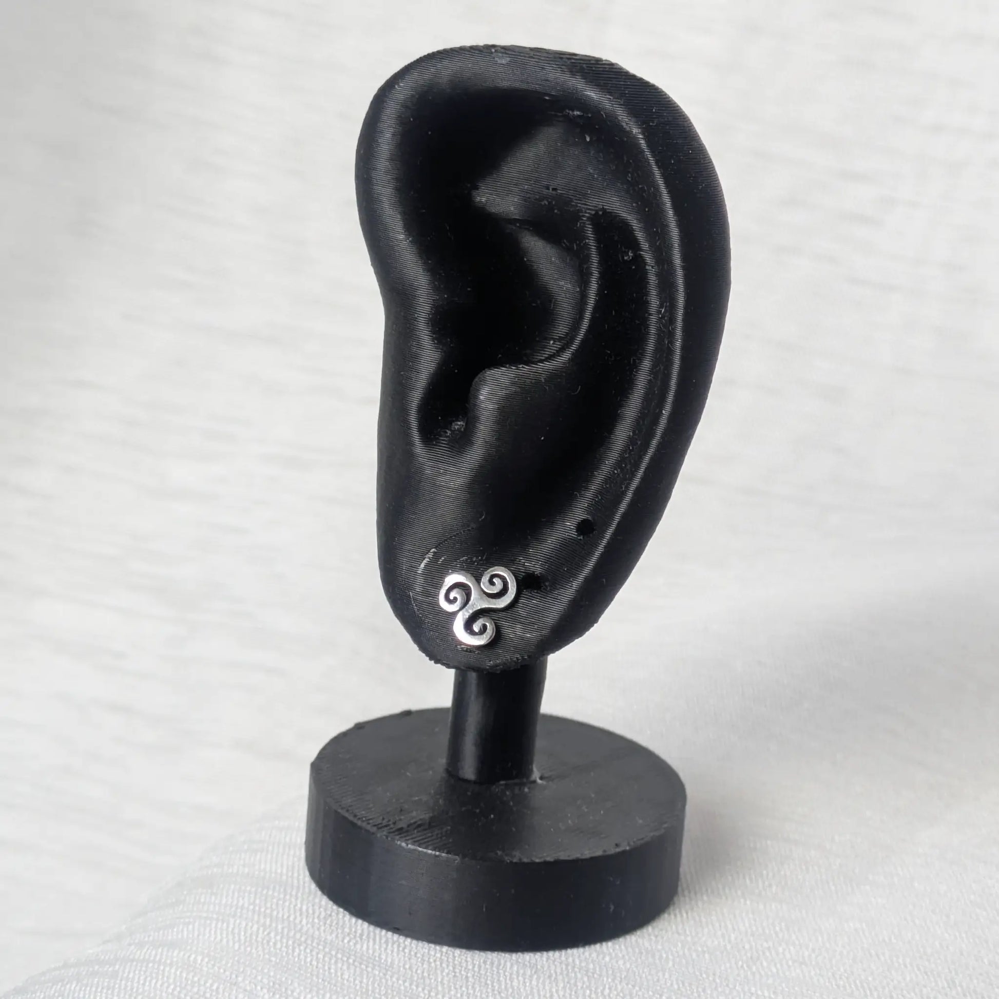 Triskele Ohrstecker aus Silber elegant präsentiert an einem schwarzen Ohr-Display
