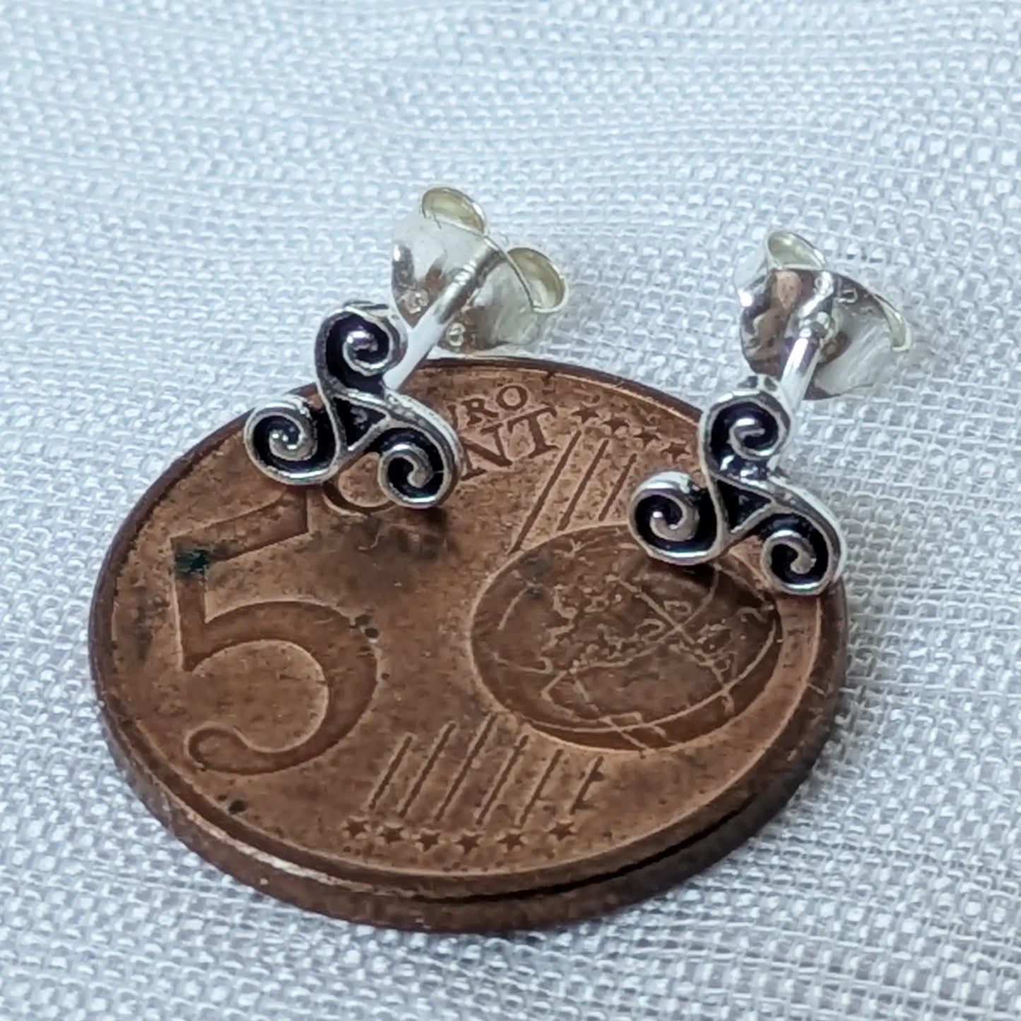 Kleine Triskel Ohrstecker 925 Silber im Größenvergleich auf einer 5-Cent-Münz