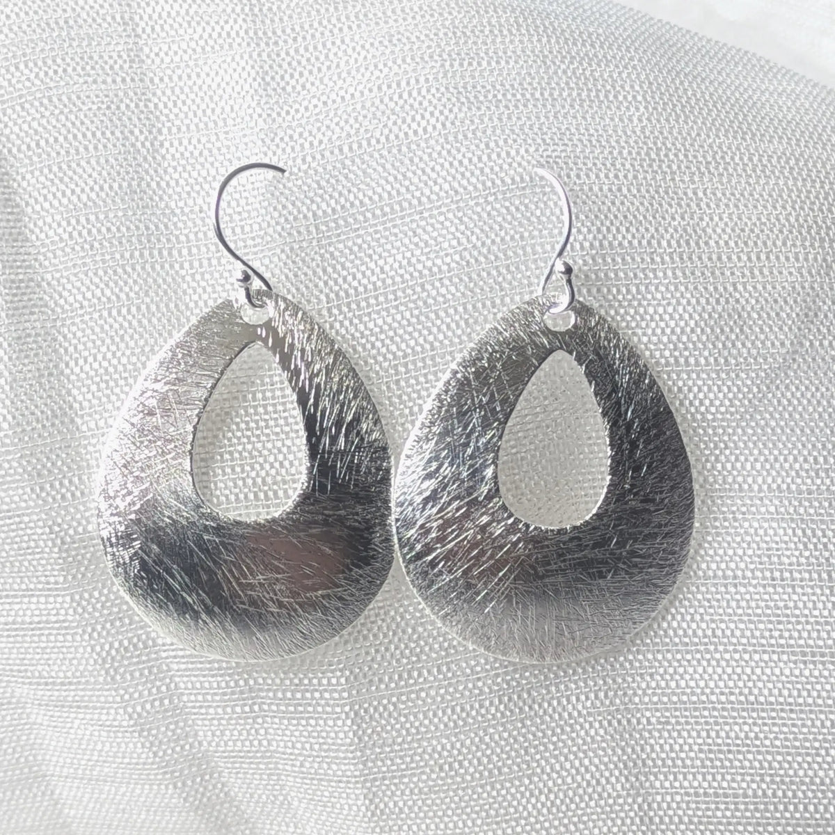 Frontalansicht der eleganten Tropfen-Ohrhänger aus 925 Sterlingsilber mit feiner Bürststruktur und zentralem Ausschnitt.
