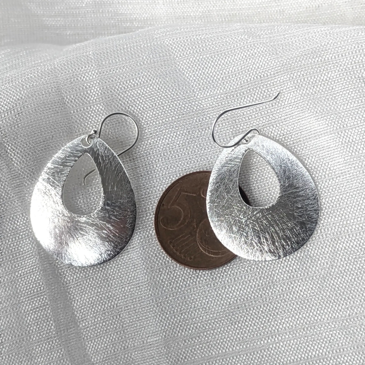 Größenvergleich der eleganten Tropfen-Ohrhänger aus Silber, flach liegend neben einer 5-Cent-Münze zur exakten Größeneinschätzung.
