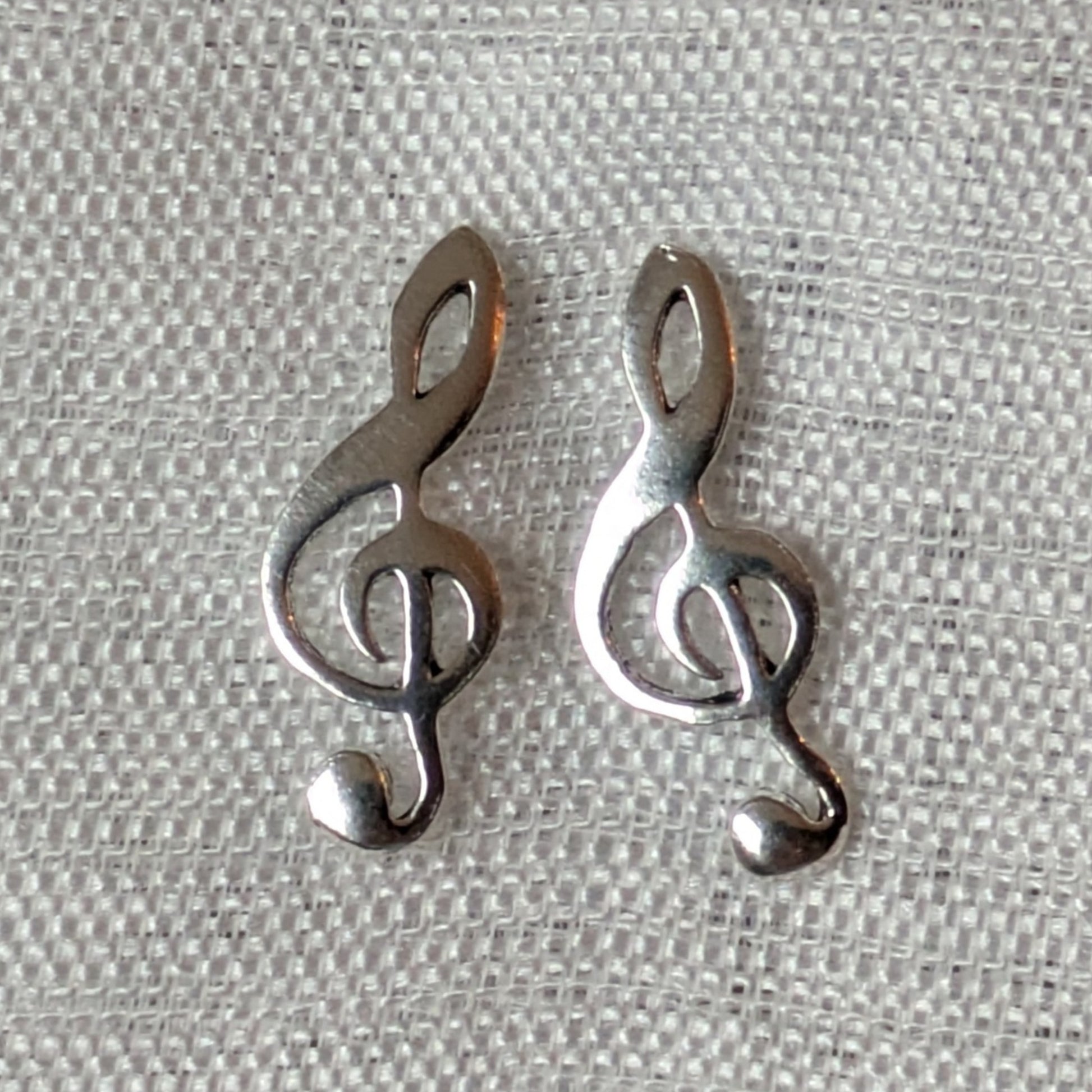 Paar Violinschlüssel Ohrstecker aus glänzendem 925 Sterling Silber in der Frontalansicht vor hellem Hintergrund.