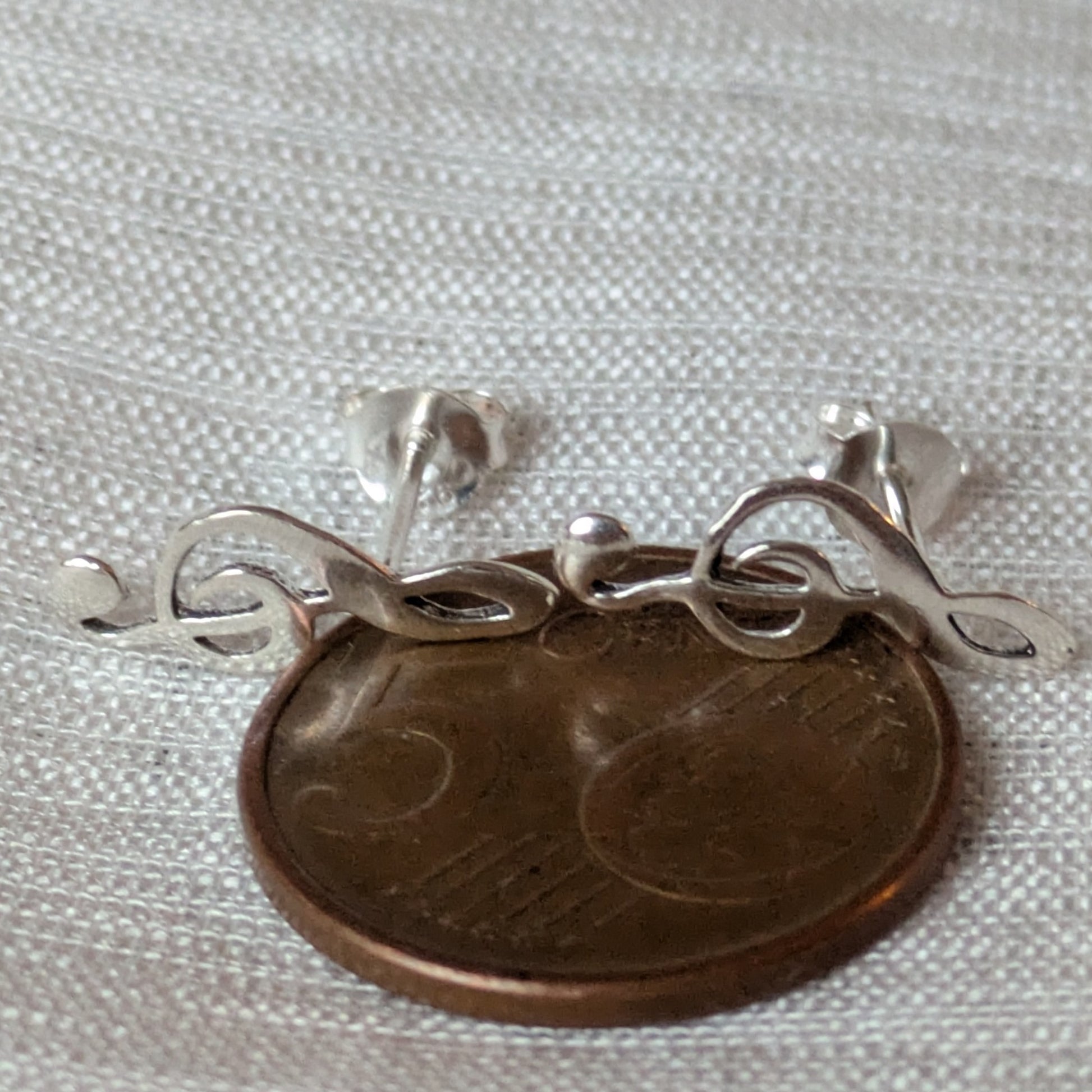 Größenvergleich der silbernen Notenschlüssel Ohrringe auf einer 5-Cent Münze zur Darstellung der kompakten, dezenten Maße.