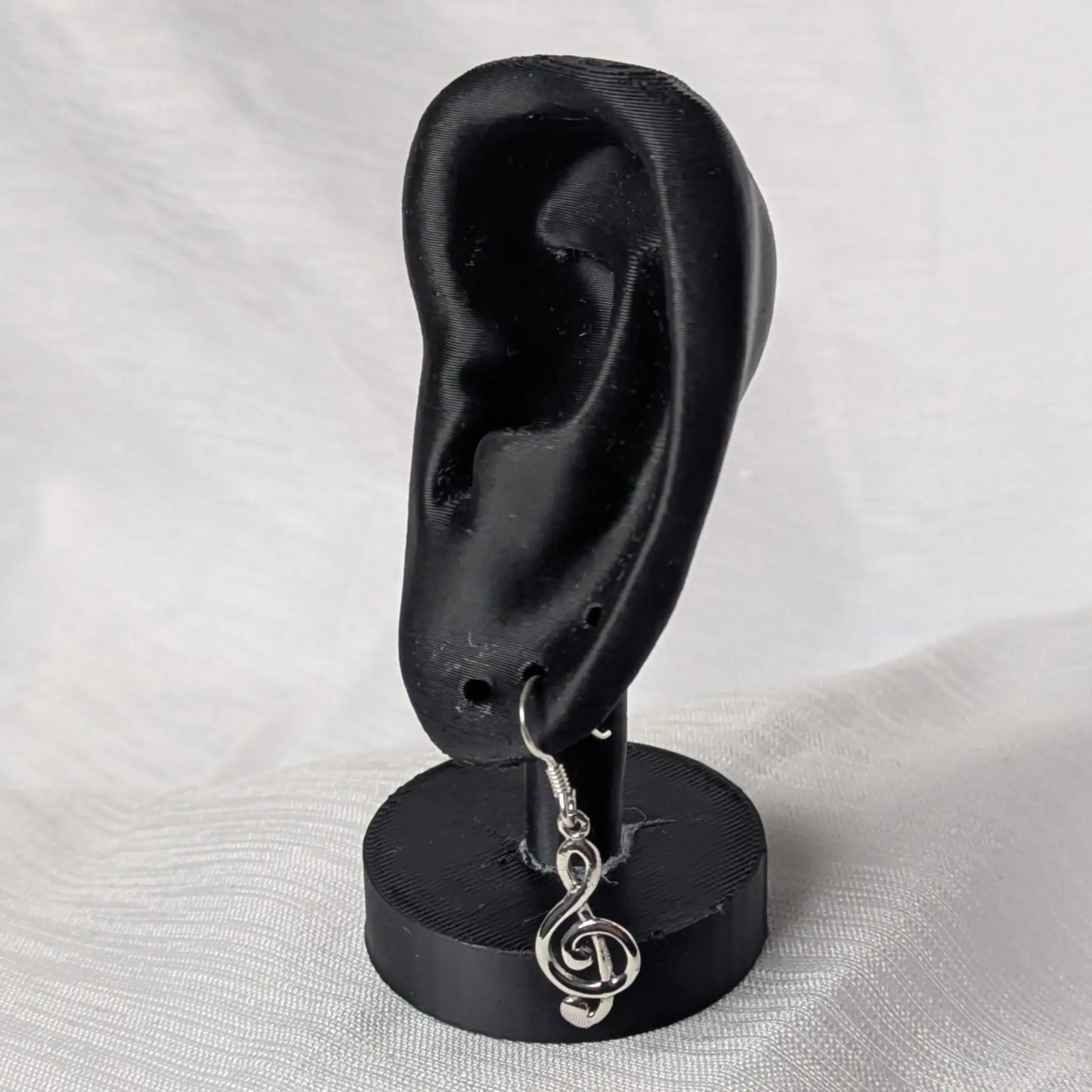 Elegante Violinschlüssel Silberohrringe an einem schwarzen Display zur Veranschaulichung der Länge.