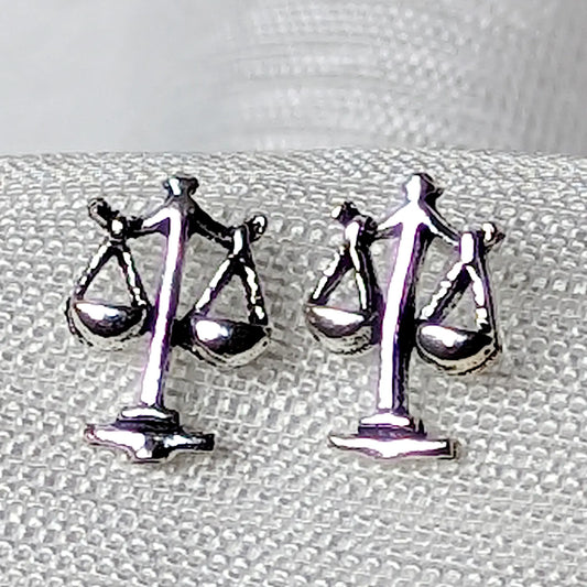 Detailreiche Nahaufnahme von zwei hochglanzpolierten Waage Ohrsteckern aus 925 Sterling Silber mit feinen Konturen.