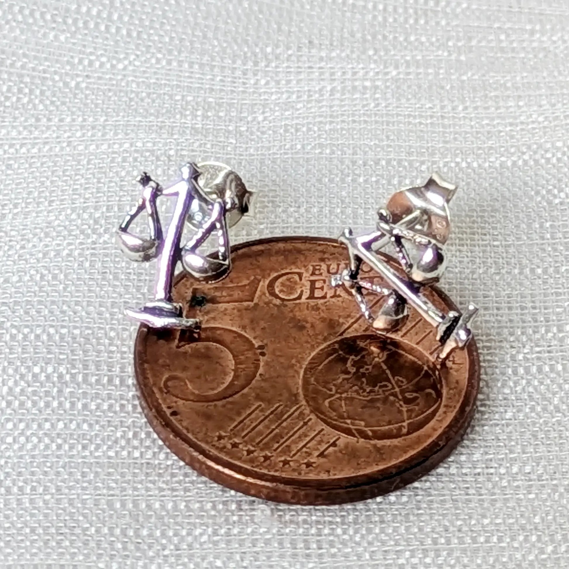 Größenvergleich der kleinen, silbernen Justitia-Ohrstecker platziert auf einer 5-Cent-Münze.