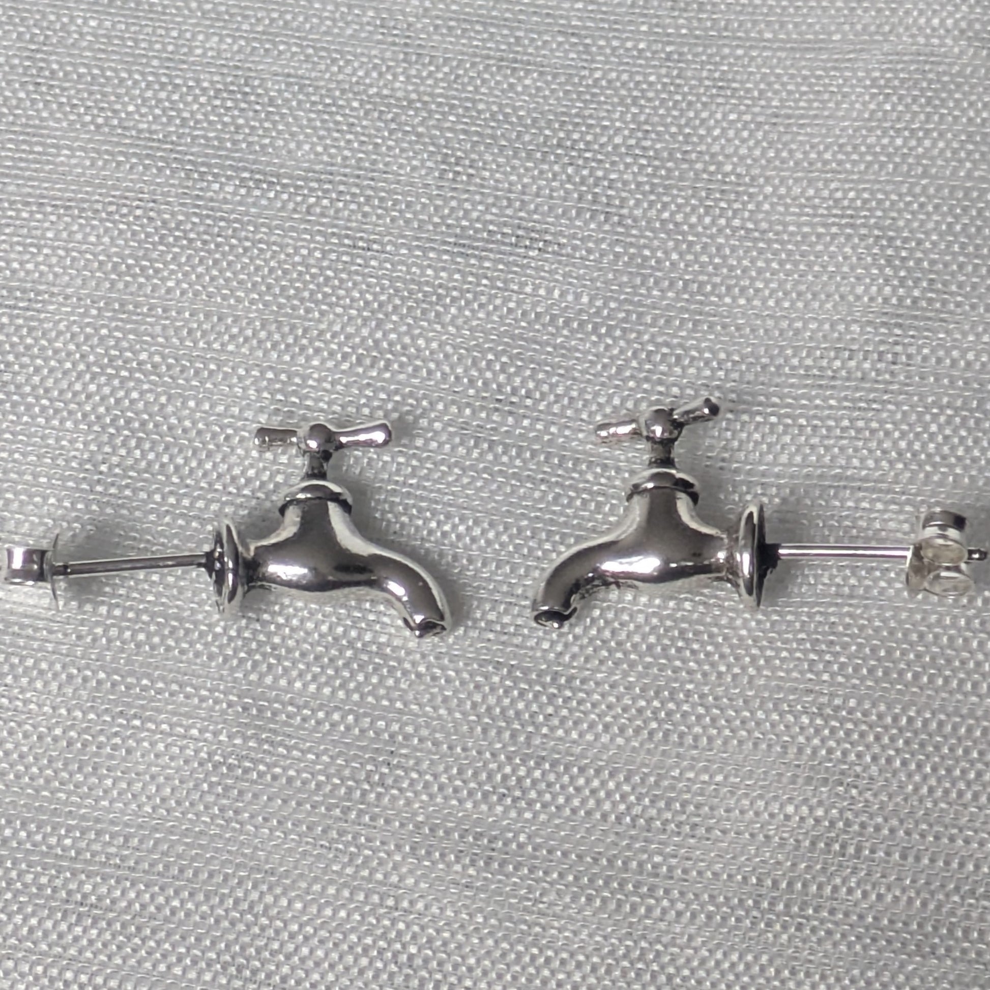 Seitliches Profil des Silber Wasserhahn Ohrsteckers, zeigt die filigrane Form und den Stecker.