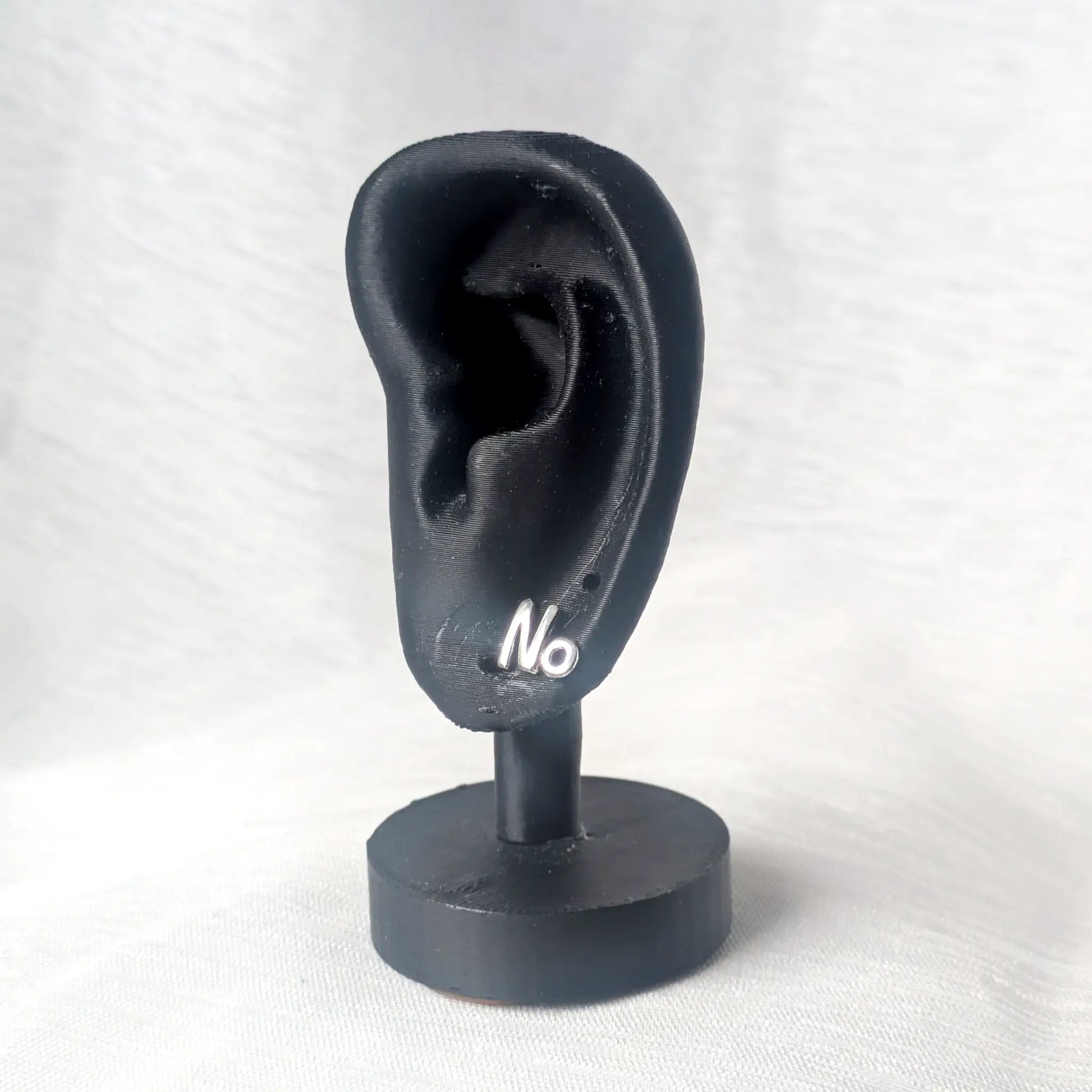 Der silberne No-Ohrstecker präsentiert an einem schwarzen Ohr-Display veranschaulicht die moderne, dezente Wirkung beim Tragen.