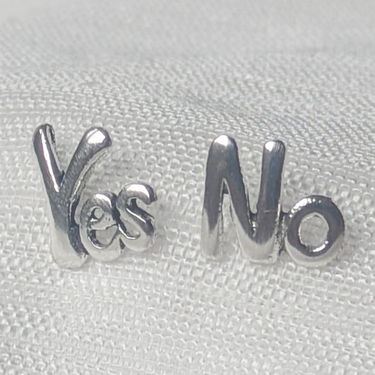 Nahaufnahme der asymmetrischen Yes No Ohrstecker aus glänzendem 925 Sterling Silber auf hellem Stoff.