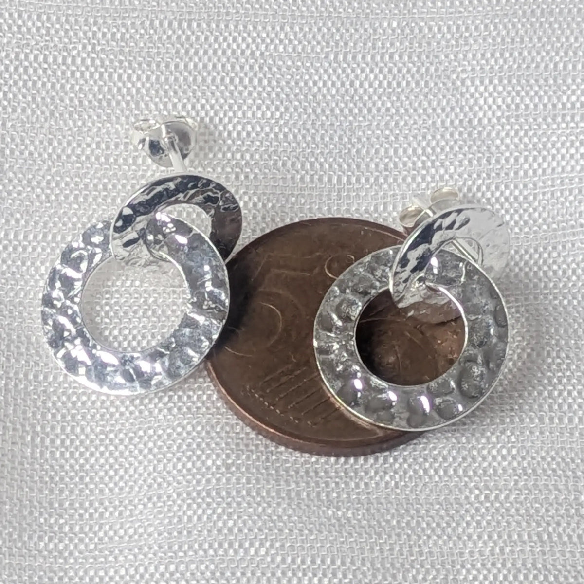 Größenvergleich gehämmerter Doppelkreis Silber-Ohrstecker liegend auf einer 5-Cent-Münze.

