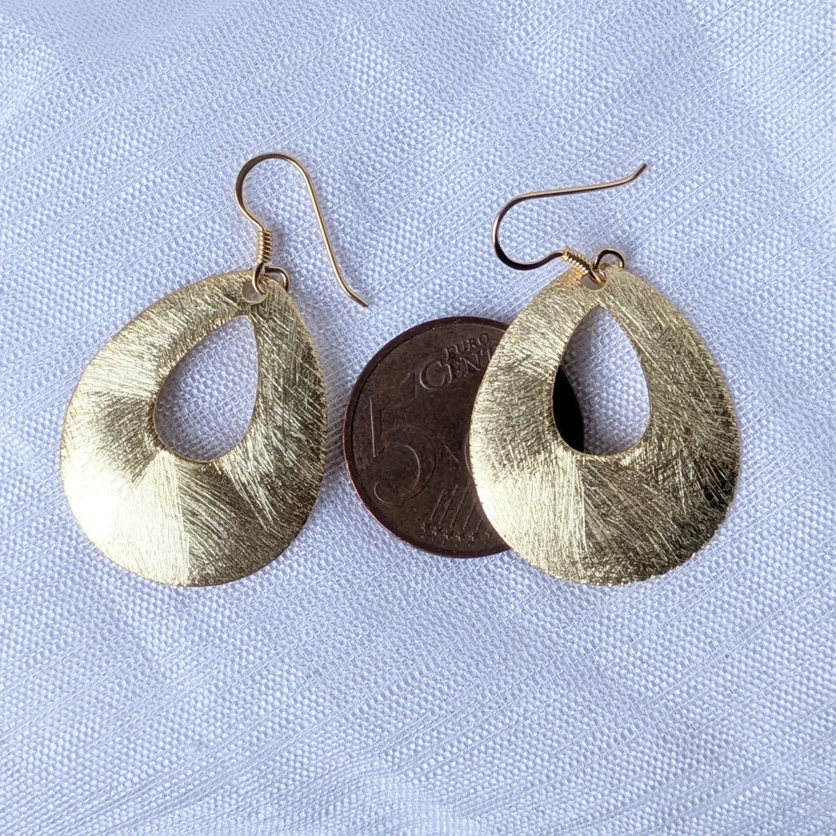 Größenvergleich der vergoldeten Tropfen-Ohrringe liegend auf einer 5-Cent-Münze zur Veranschaulichung der Dimensionen.
