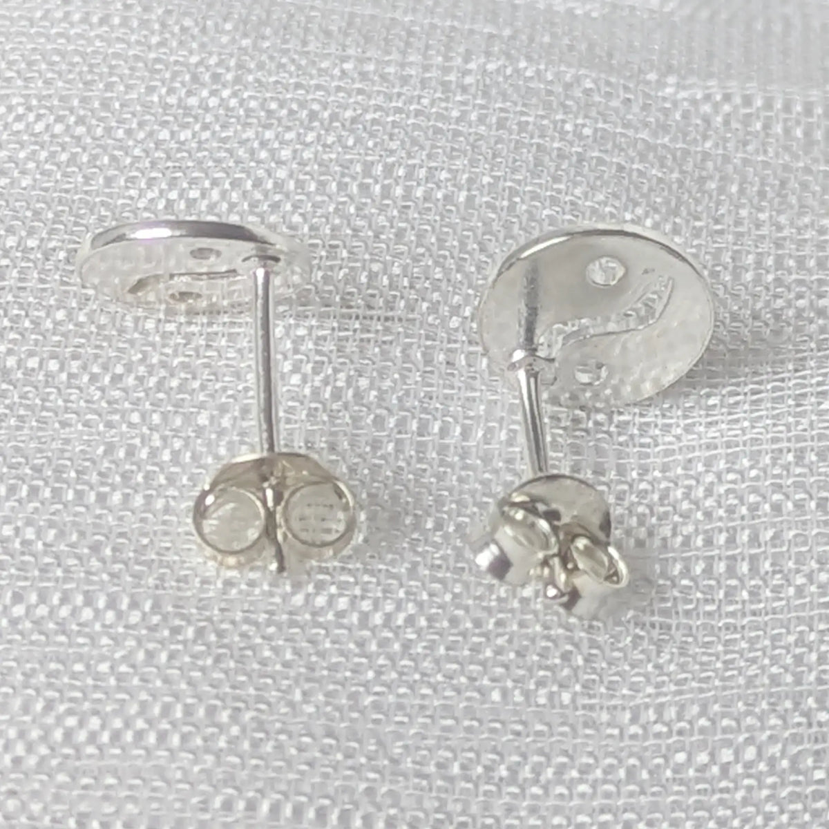 Rückseite der flachen silbernen Yin-Yang-Stecker.