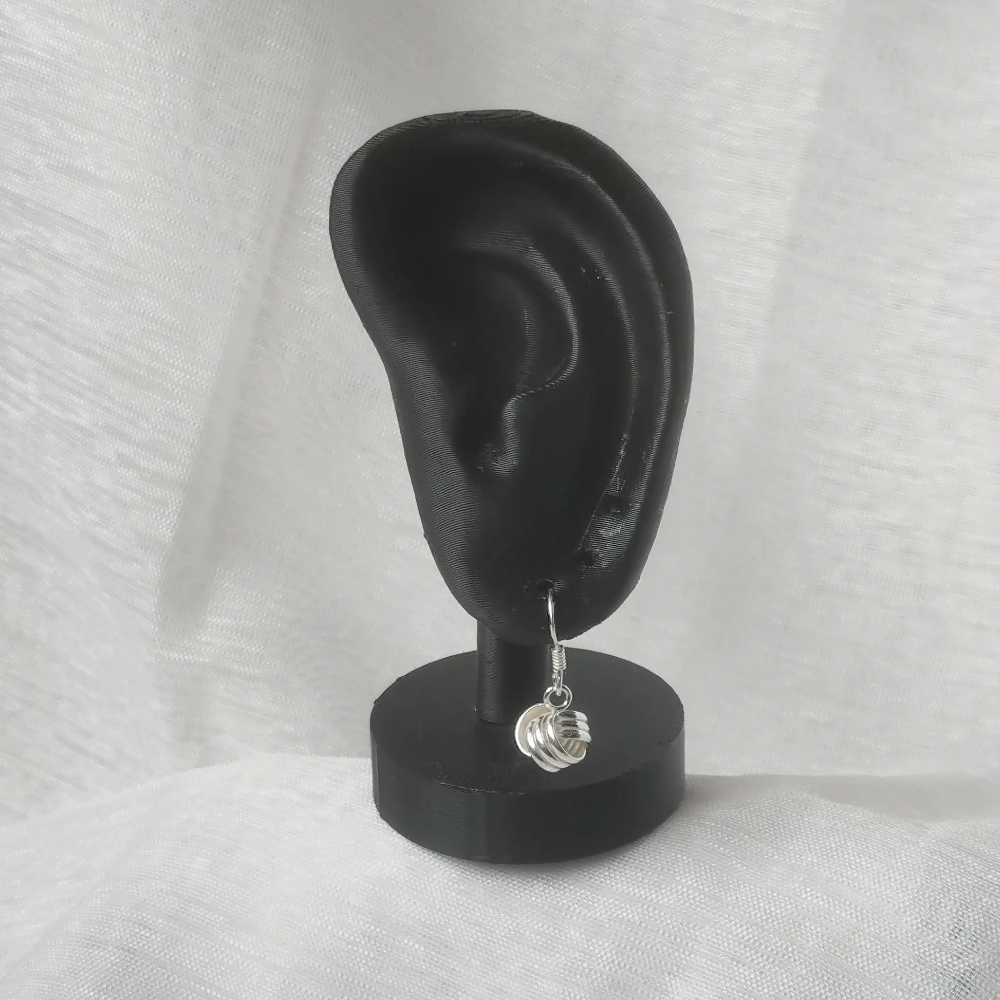 Elegante Hängeohrringe mit Knoten aus 925 Silber am schwarzen Ohr-Displa