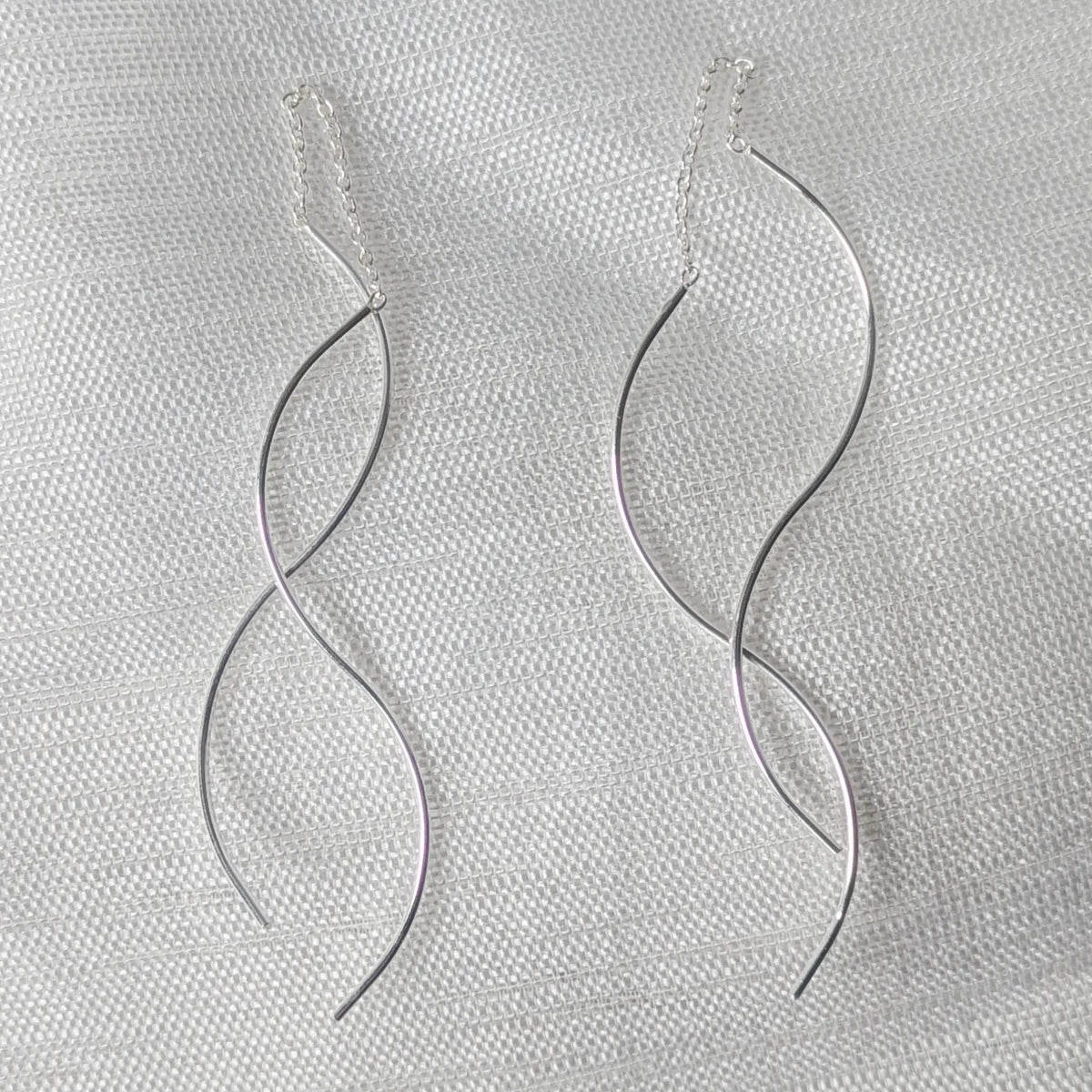 Nahaufnahme der langen Durchzieher Ohrringe aus 925 Silber mit feiner Kette und doppelt geschwungenem Wellen-Design